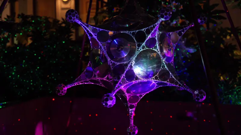 Close-up of a mirrored kinetic sculpture lit purple and blue at night