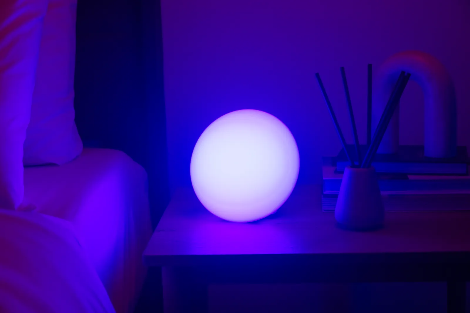 A small projector casting slow stars and colour across a dark bedroom ceiling